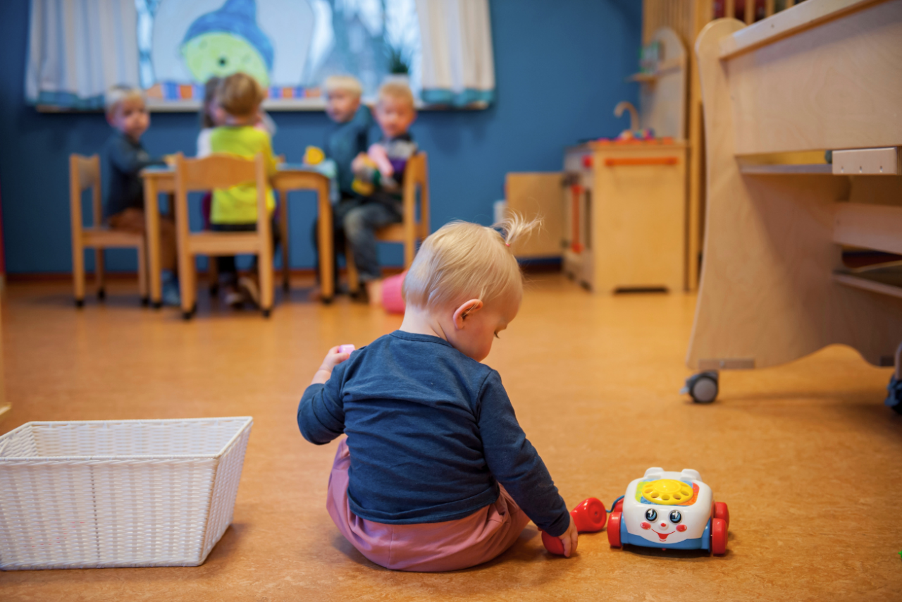 KDV, dreumes op de grond spelen met speelgoedtelefoon