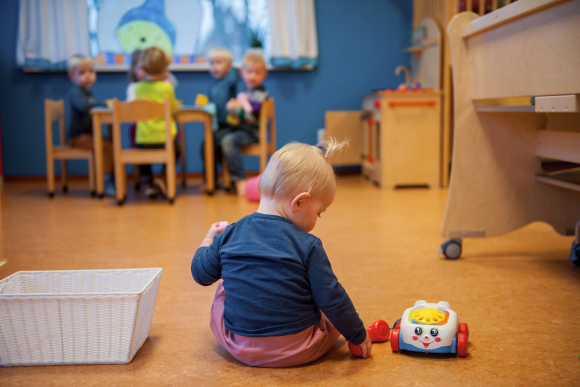 KDV, dreumes op de grond spelen met speelgoedtelefoon